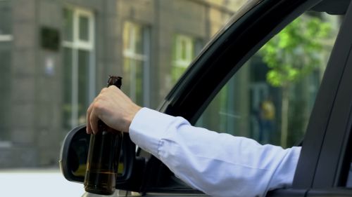 Man holding beer bottle outside his car window