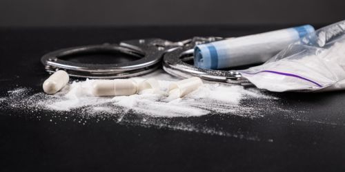 handcuffs with drugs on the table close-up, concept of law and drugs