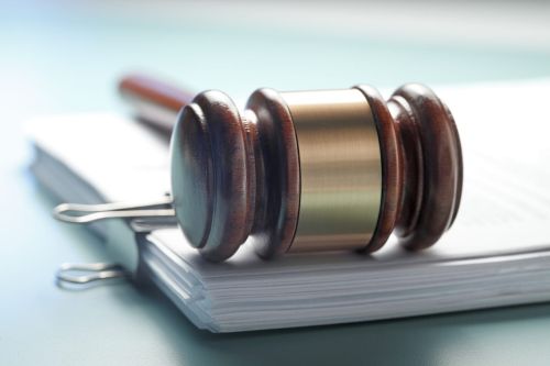 A gavel rests on top of a stack of legal documents bound together by a large clip. Visual concept for a legal blog on plea bargaining with legal counsel.