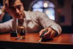 One drunk man sitting at bar counter, holding car keys. Visual concept for legal blog: Is Operating While Intoxicated A Felony In Michigan?
